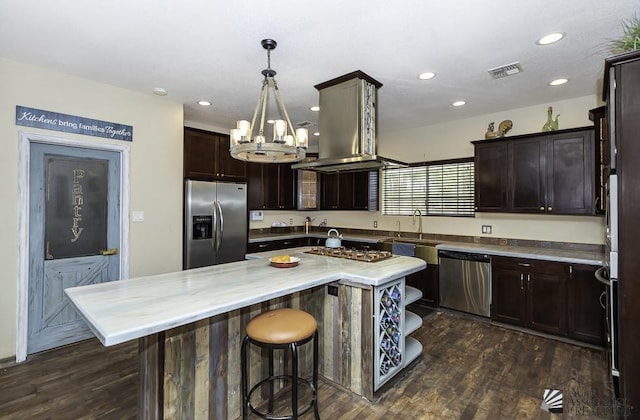 kitchen featuring dark wood-style floors, a center island, a breakfast bar area, stainless steel appliances, and dark brown cabinetry