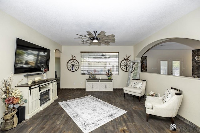 living area with plenty of natural light, arched walkways, and wood finished floors