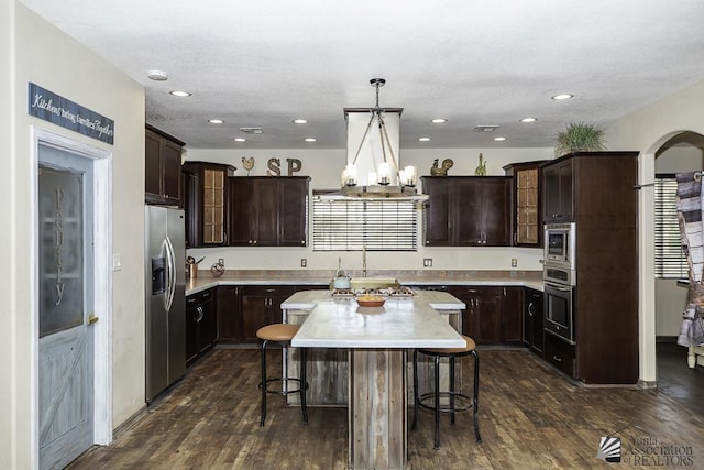 kitchen featuring stainless steel appliances, a kitchen breakfast bar, dark wood finished floors, and dark brown cabinets