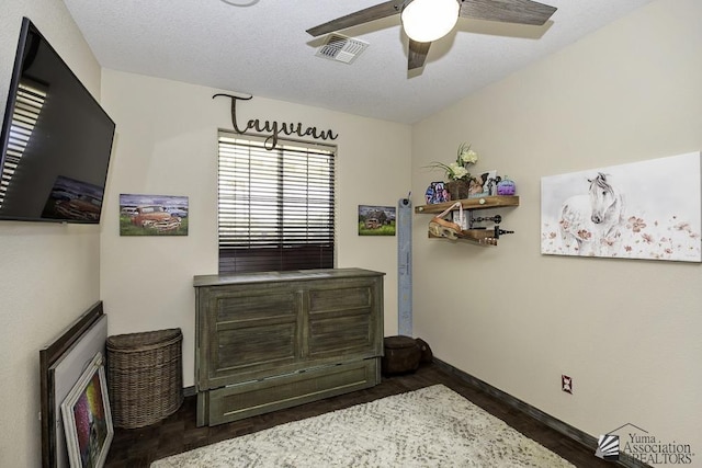 bedroom with baseboards, visible vents, a ceiling fan, dark wood-style flooring, and a textured ceiling