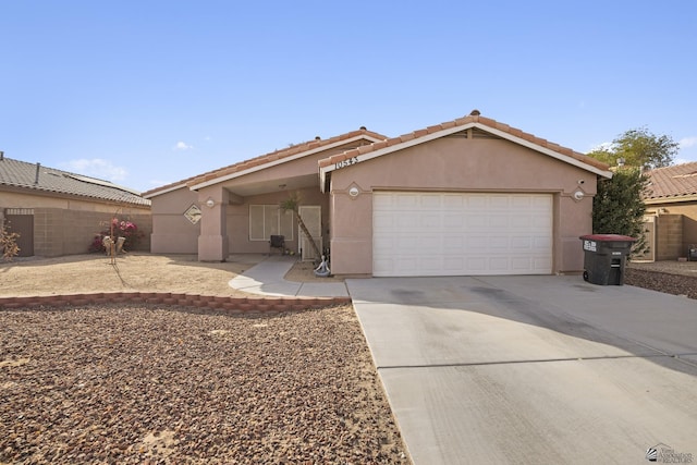 ranch-style house featuring a garage, stucco siding, fence, and concrete driveway