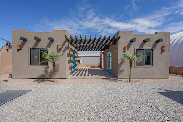 pueblo-style house with a patio, stucco siding, and a pergola