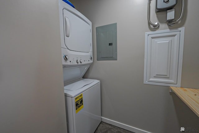 washroom featuring baseboards, laundry area, stacked washer / dryer, and electric panel