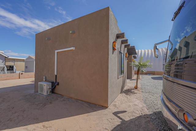 view of property exterior featuring fence, ac unit, and stucco siding