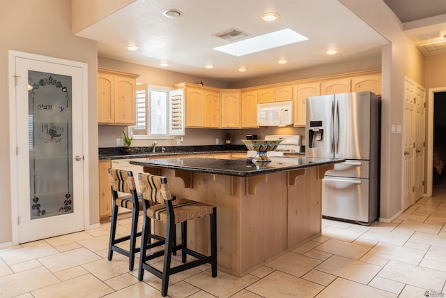11519 E Del Verde St, Yuma, AZ 85367 - kitchen with white microwave, stainless steel fridge with ice dispenser, range with gas cooktop, light brown cabinetry, and a breakfast bar area