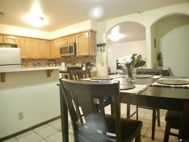 dining space with arched walkways, visible vents, and light tile patterned floors