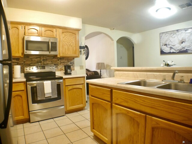 kitchen with visible vents, decorative backsplash, light tile patterned flooring, a sink, and appliances with stainless steel finishes