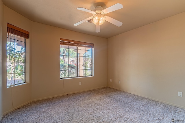 carpeted spare room featuring ceiling fan and a healthy amount of sunlight