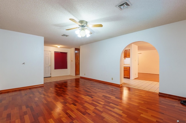 1409 S Howard Dr, Yuma, AZ 85364 - empty room featuring ceiling fan, light wood-type flooring, arched walkways, baseboards, and a textured ceiling
