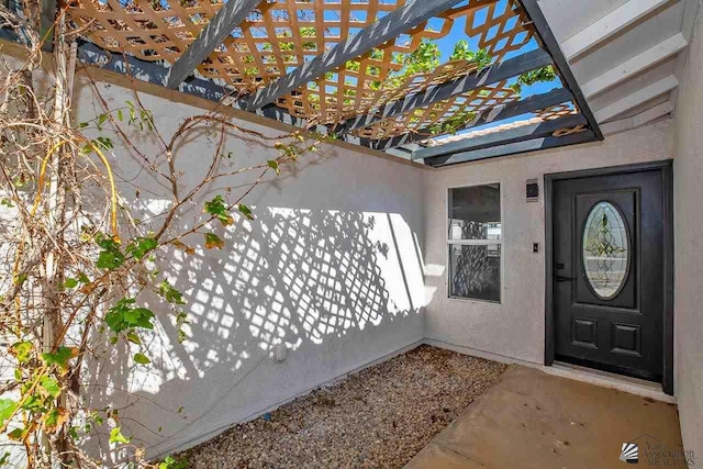 entrance to property featuring stucco siding and a pergola
