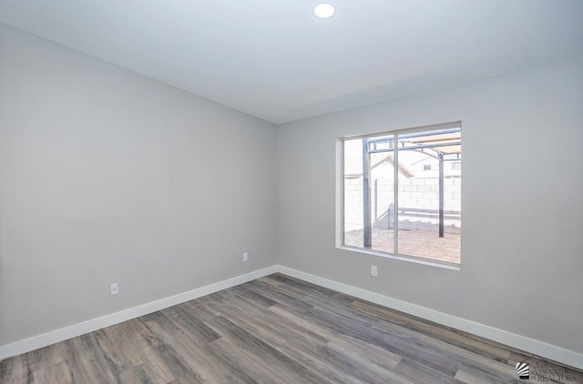 empty room with wood finished floors, baseboards, and recessed lighting