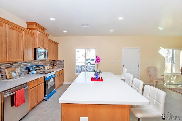 13459 E 43rd Ln, Yuma, AZ 85367 - kitchen with a kitchen breakfast bar, backsplash, a kitchen island, and stainless steel appliances