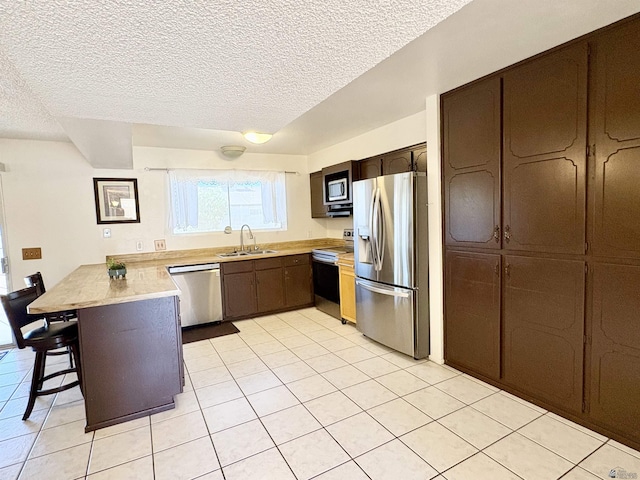 4447 W 14th Pl, Yuma, AZ 85364 - kitchen with stainless steel appliances, a peninsula, light tile patterned flooring, light countertops, and a textured ceiling