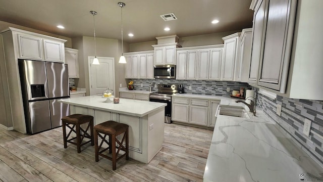 11569 Sonora St, Wellton, AZ 85356 - kitchen with appliances with stainless steel finishes, a kitchen island, tasteful backsplash, light stone countertops, and recessed lighting