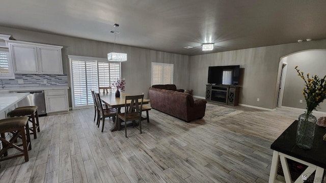 11569 Sonora St, Wellton, AZ 85356 - dining area with light wood-style flooring, arched walkways, baseboards, and a chandelier