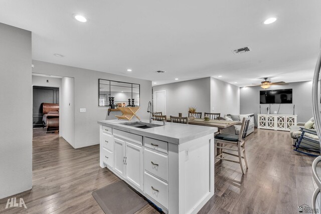 1428 W 15th St, Yuma, AZ 85364 - kitchen featuring a sink, a ceiling fan, a kitchen island with sink, wood finished floors, and white cabinetry