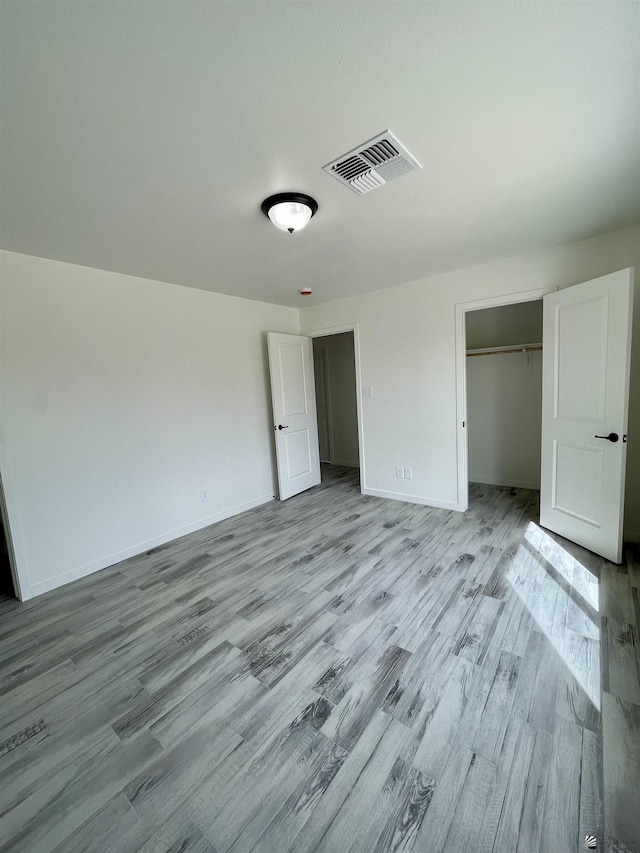 unfurnished bedroom with visible vents, baseboards, wood finished floors, and a closet