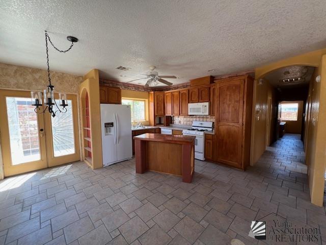 13257 E 55th Dr, Yuma, AZ 85367 - kitchen with white appliances, arched walkways, a textured ceiling, a center island, and visible vents