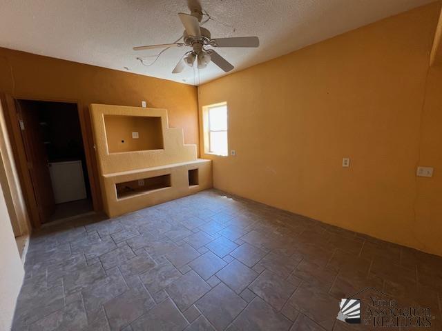 13257 E 55th Dr, Yuma, AZ 85367 - unfurnished living room with a textured ceiling, a ceiling fan, and stone tile flooring