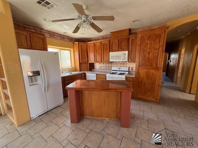 13257 E 55th Dr, Yuma, AZ 85367 - kitchen with visible vents, white appliances, ceiling fan, a center island, and arched walkways