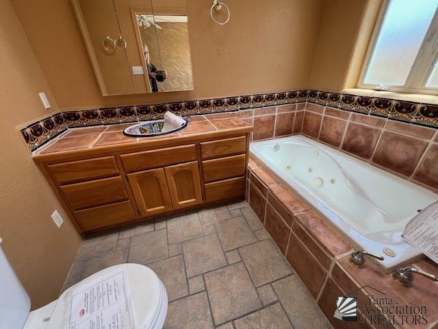 13257 E 55th Dr, Yuma, AZ 85367 - full bathroom featuring vanity, a tub with jets, and stone tile flooring