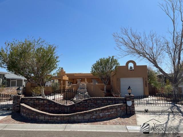 13257 E 55th Dr, Yuma, AZ 85367 - view of front of house with driveway, a fenced front yard, a gate, a garage, and stucco siding