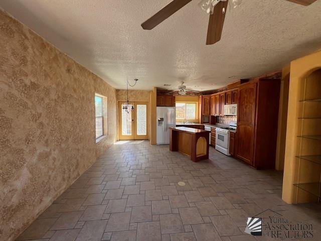 13257 E 55th Dr, Yuma, AZ 85367 - kitchen featuring a ceiling fan, a textured ceiling, a kitchen island, and white appliances
