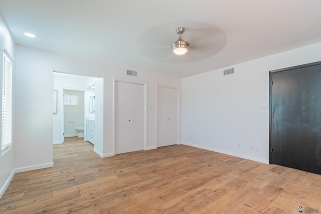 1087 W Palmcroft Dr, Yuma, AZ 85364 - unfurnished bedroom featuring two closets, light wood-type flooring, multiple windows, and ensuite bathroom