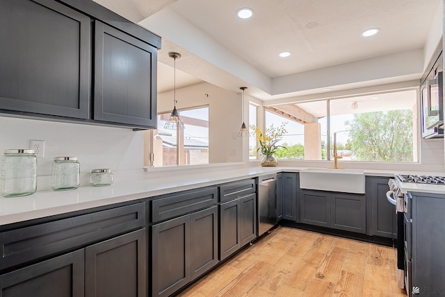 1087 W Palmcroft Dr, Yuma, AZ 85364 - kitchen featuring range with gas stovetop, stainless steel dishwasher, light countertops, light wood-style floors, and hanging light fixtures