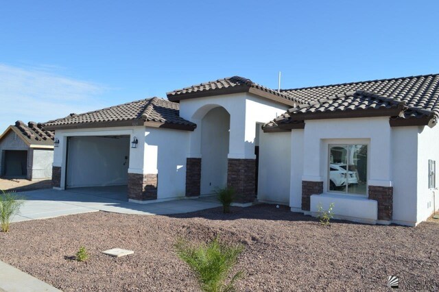 13135 E 55th Ln Lot 18, Yuma, AZ 85367 - mediterranean / spanish-style house featuring a tile roof, stone siding, a garage, stucco siding, and concrete driveway