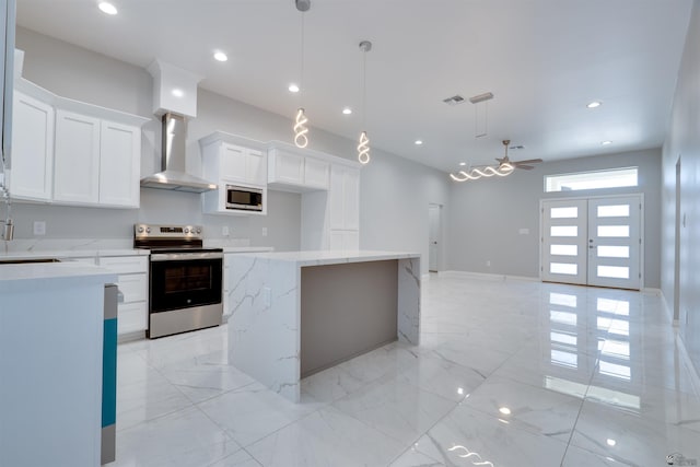 kitchen with a center island, recessed lighting, wall chimney exhaust hood, white cabinets, and appliances with stainless steel finishes
