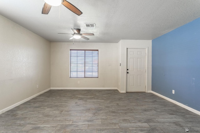 empty room featuring visible vents, wood finished floors, baseboards, ceiling fan, and a textured ceiling