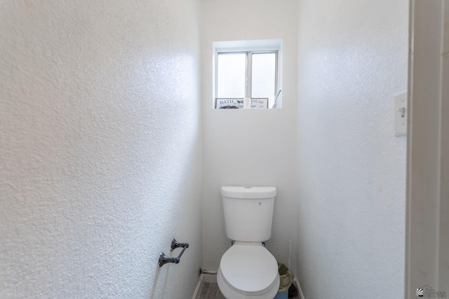 bathroom with a textured wall and toilet