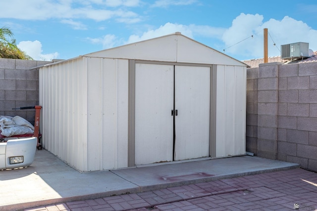 view of shed with fence and cooling unit