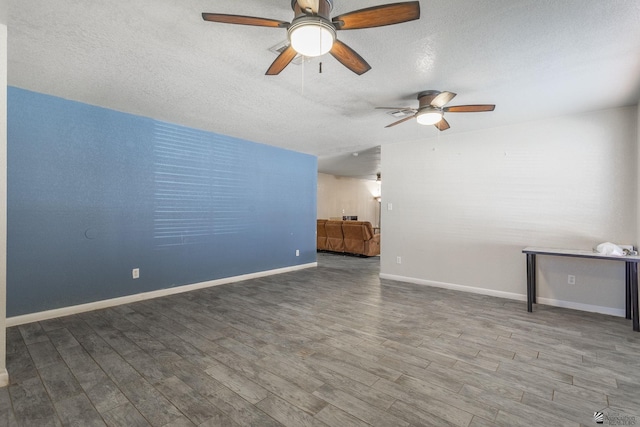 unfurnished living room with baseboards, a ceiling fan, a textured ceiling, and wood finished floors