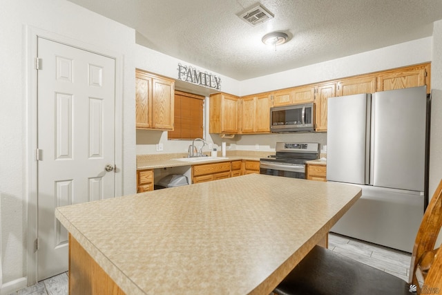 kitchen featuring a textured ceiling, visible vents, appliances with stainless steel finishes, a sink, and light countertops