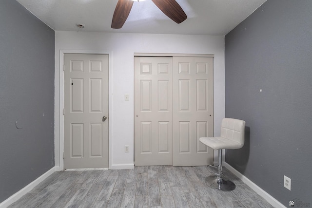 unfurnished bedroom with baseboards, ceiling fan, wood finished floors, and a closet