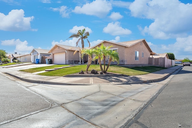 ranch-style house featuring driveway, a front yard, fence, an attached garage, and stucco siding