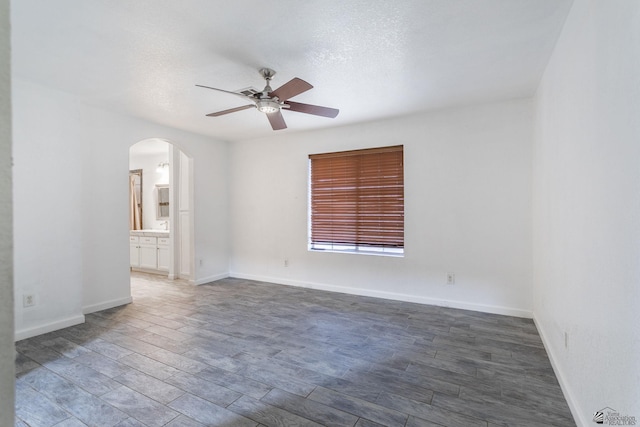 unfurnished room with arched walkways, a textured ceiling, ceiling fan, and wood finished floors