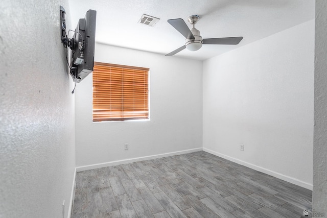 unfurnished room with visible vents, a ceiling fan, baseboards, and wood finished floors
