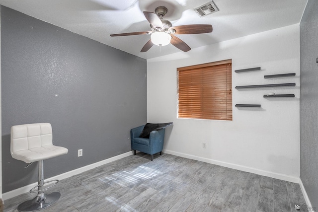 unfurnished room featuring baseboards, a ceiling fan, wood finished floors, and visible vents