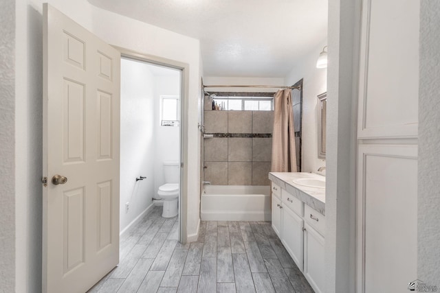 full bathroom with shower / bath combination with curtain, wood finished floors, vanity, baseboards, and toilet