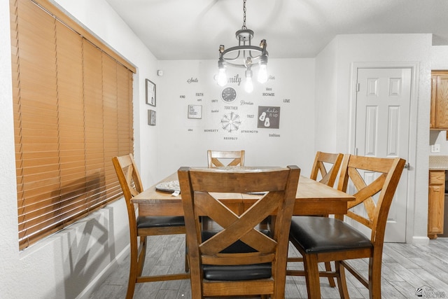 dining area with baseboards, light wood finished floors, and a chandelier