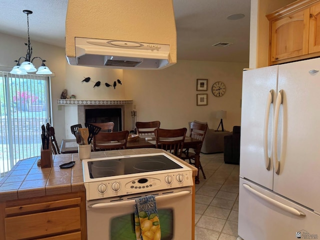 14818 E 52nd St, Yuma, AZ 85367 - kitchen featuring a fireplace, white appliances, tile countertops, light tile patterned floors, and hanging light fixtures