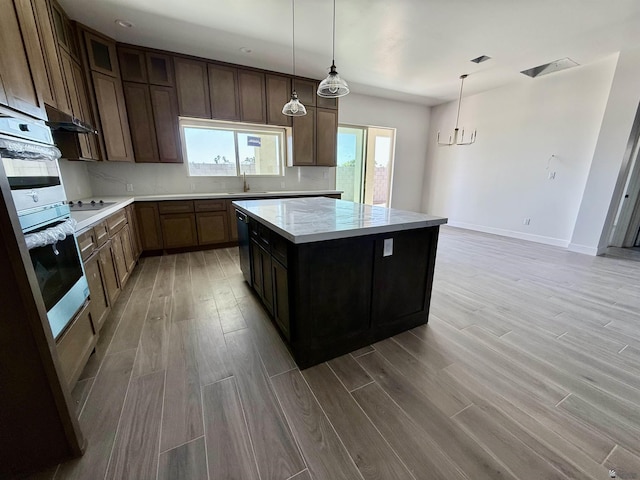 12377 W Calle Ln, Primera, Yuma, AZ 85367 - kitchen with baseboards, a center island, light countertops, a sink, and light wood-style flooring