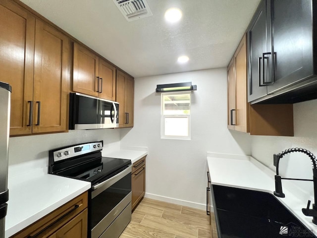 2461 S 17th Ave, Yuma, AZ 85364 - kitchen featuring stainless steel range with electric stovetop, brown cabinetry, light wood finished floors, light countertops, and recessed lighting
