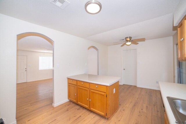 2794 W 27th Ln, Yuma, AZ 85364 - kitchen with arched walkways, light wood finished floors, ceiling fan, light countertops, and a peninsula