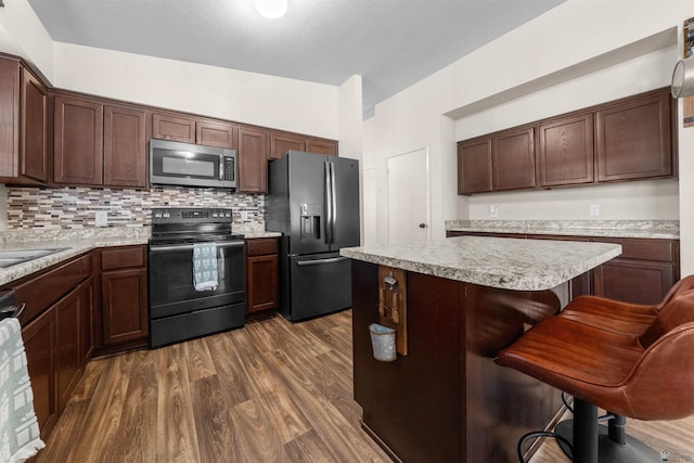 4841 W 10th Pl, Yuma, AZ 85364 - kitchen with stainless steel microwave, black electric range oven, refrigerator with ice dispenser, dark wood-type flooring, and light countertops