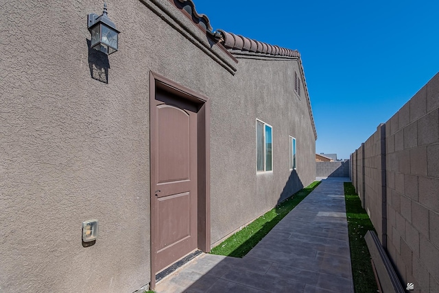 view of home's exterior with fence, a tile roof, and stucco siding