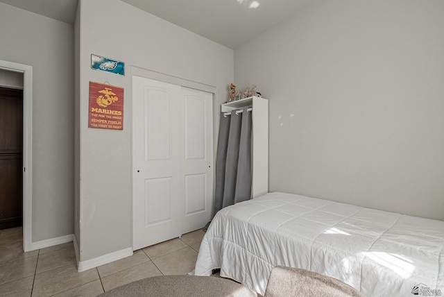 bedroom featuring light tile patterned flooring, baseboards, and a closet